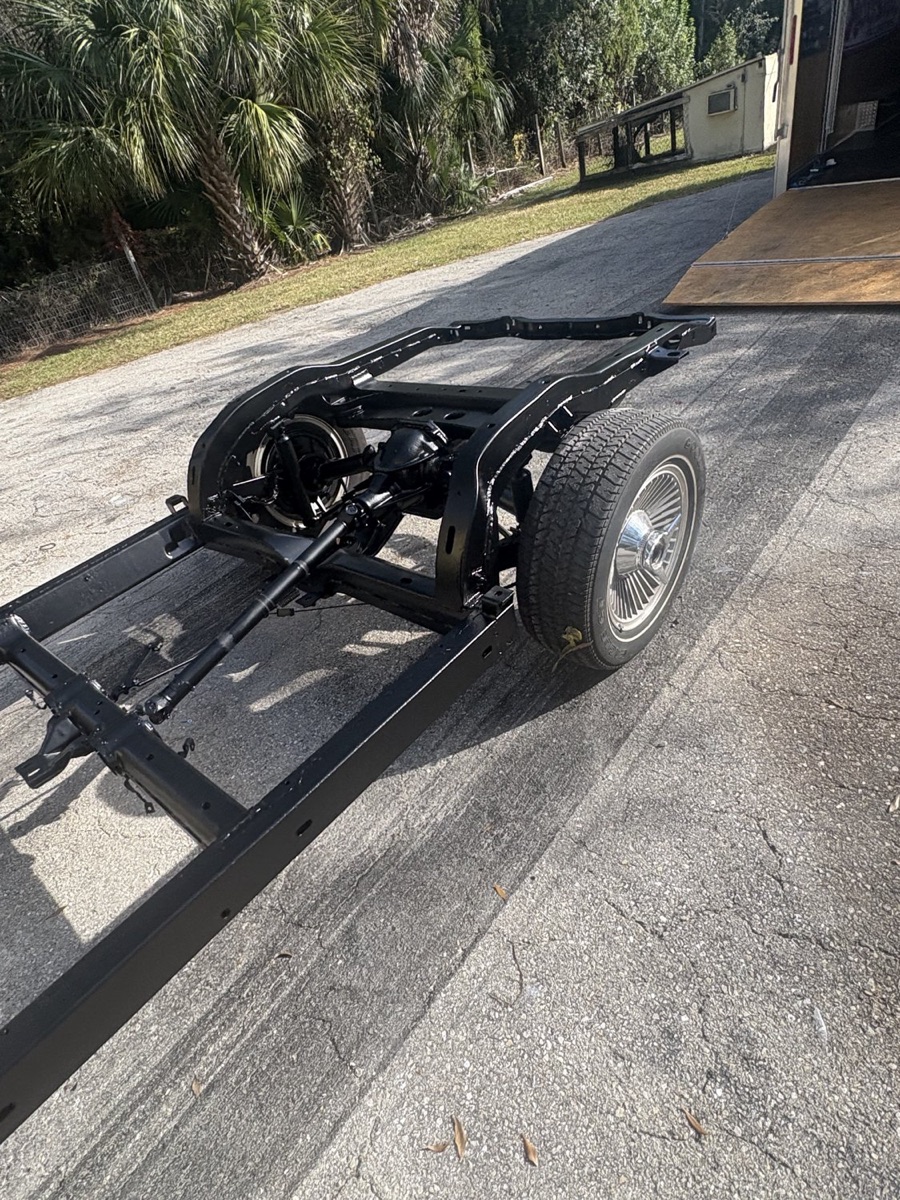 Freshly coated black truck frame mounted on a trailer, ready for reassembly