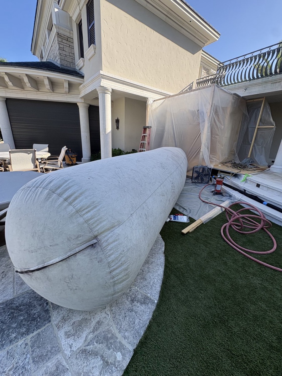 Boat hull draped and prepped for wet blasting on stands